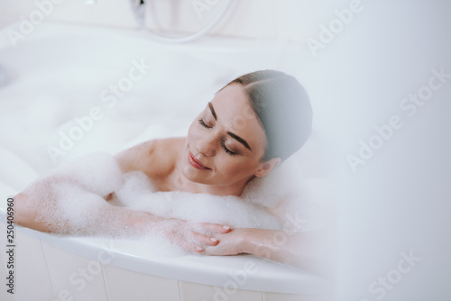 Leinwand Poster Delighted nice woman enjoying warm bath after working days