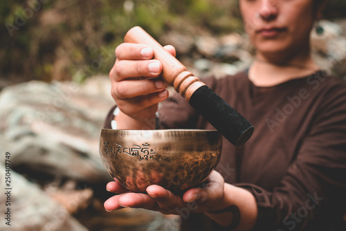 woman holding and playing a singing bowl tibetan bowl