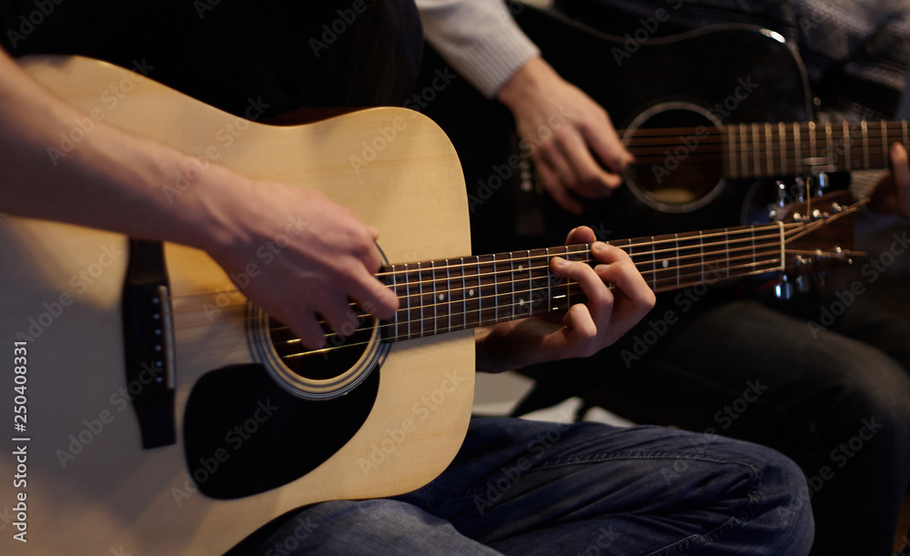 Obraz premium Two people duet playing a melody on acoustic six-string guitars at home in ordinary everyday clothes