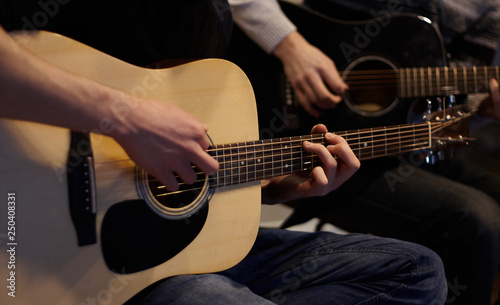 Two people duet playing a melody on acoustic six-string guitars at home in ordinary everyday clothes