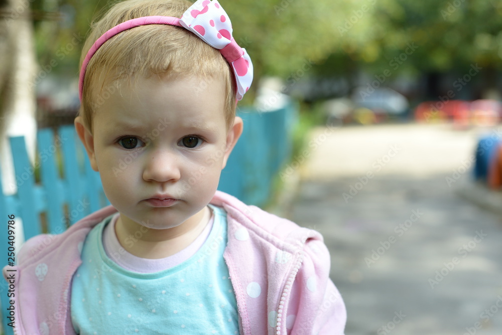 Portrait of beautiful little baby girl, looking straight into the camera.  Serious toddler outside. Pretty caucasian