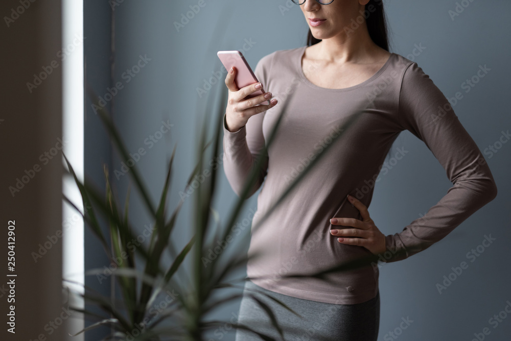 Cropped photo of brunette woman with smartphone in arms indoors