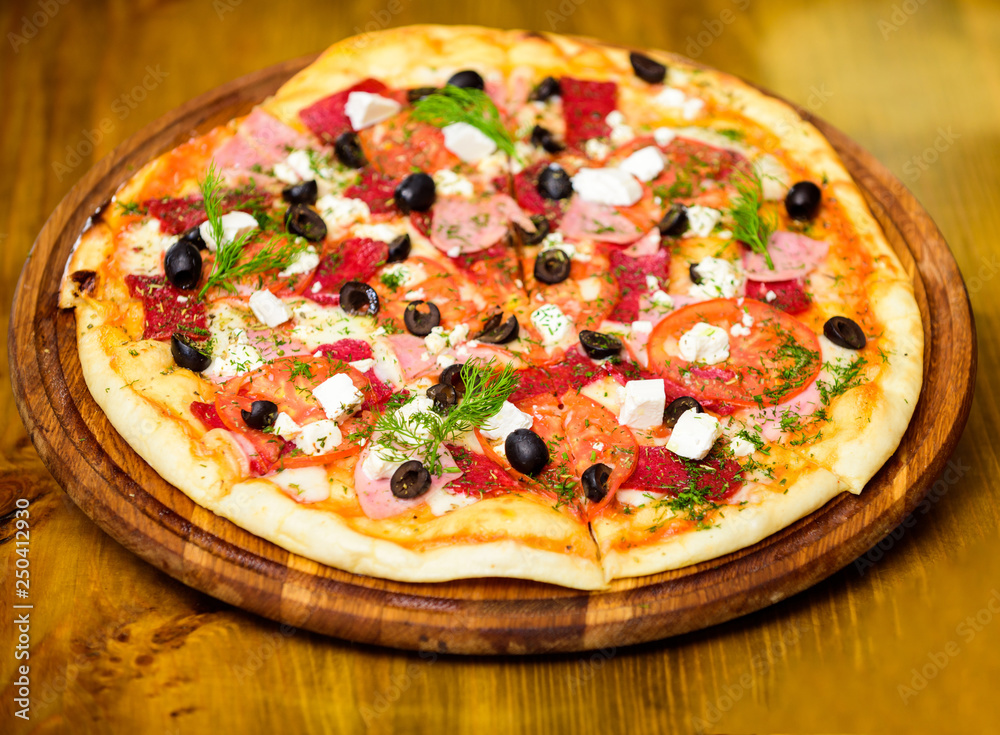 Pizza served with dill. Pizza with tomatoes black olives and ham. Take away food concept. Pizzeria restaurant. Italian pizza concept. Delicious hot pizza on wooden board plate. Food delivery service