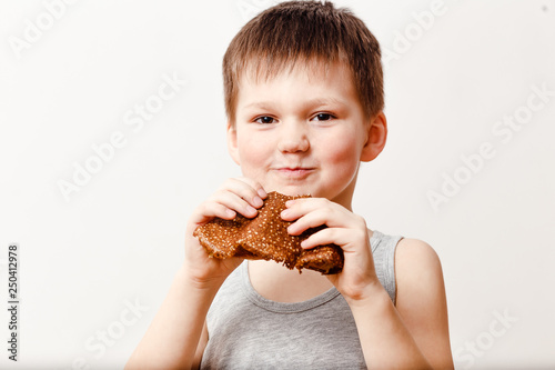 a five-year-old Russian boy in a gray t-shirt eats an oil pancake on a white background. Maslenitsa
