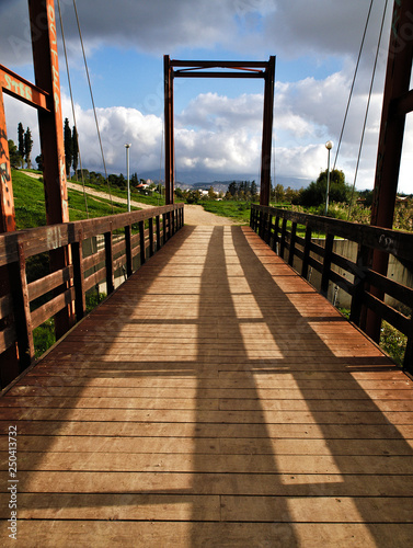 Pedestrian wooden blocks bridge in a park , perspective photo. Bridge above lake in a park. Tritsis enviromental park in Athens Greece. photo