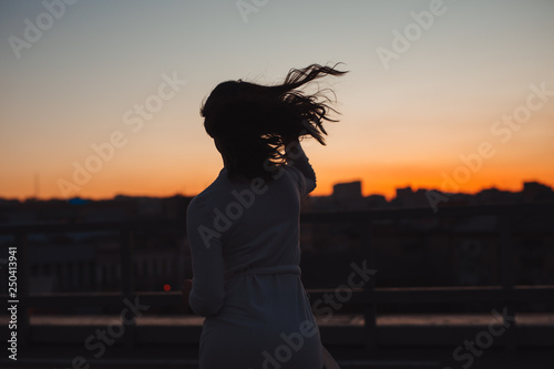 Silhouette of woman run into sunset in city