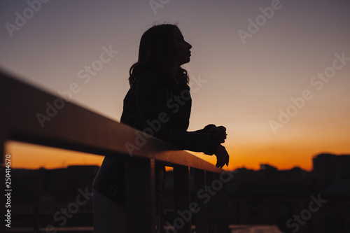 Silhouette of woman thinking about future at sunset in city