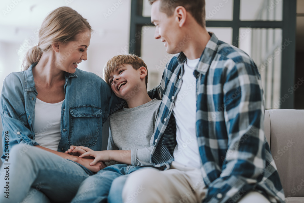 Happy boy sitting between his parents and laughing Happy boy sitting between his parents and laughing