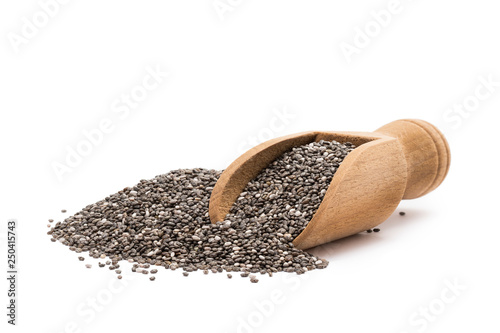 Pile or heap of chia seeds and a small wooden scoop seen from the front and isolated on white background