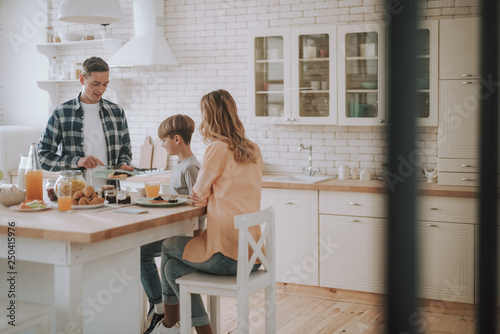Schilderij op canvas Family of three having breakfast in the kitchen