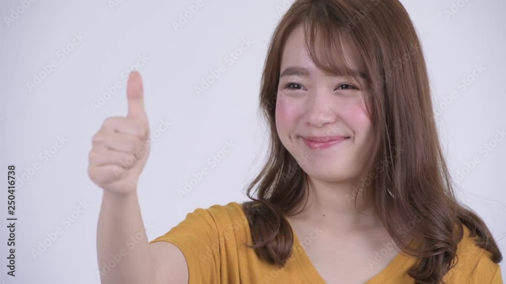 Face of happy young beautiful Asian woman giving thumbs up Face of happy young beautiful Asian woman giving thumbs up