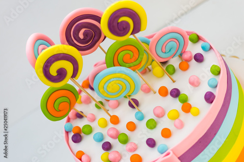 Birthday cake with colorful lollipops on a white background