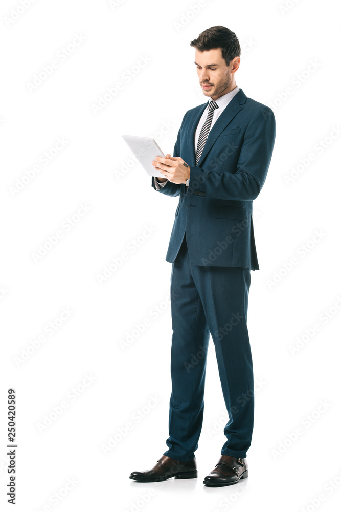 serious businessman in suit using digital tablet isolated on white