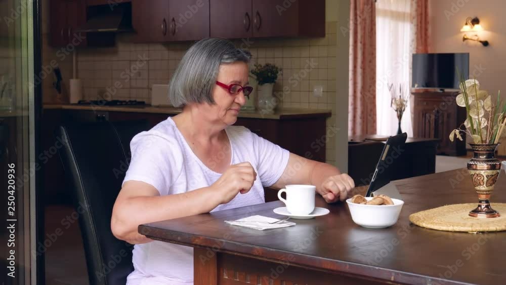 Technology, age and people concept - happy senior woman with tablet pc computer at home. Handheld slow motion 4k Technology, age and people concept - happy senior woman with tablet pc computer at home. Handheld slow motion 4k