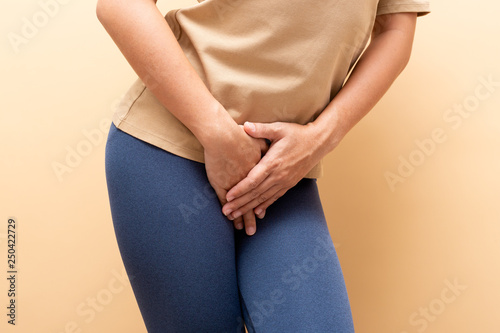 Valokuva Closeup sick woman with hands holding pressing her crotch isolated on background