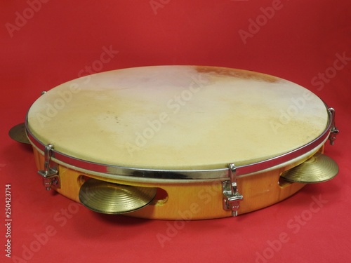 Close-up of a pandeiro (tambourine), a Brazilian percussion musical instrument, on a pink background. The instrument is widely used to accompany samba and choro, two popular Brazilian rhythms.