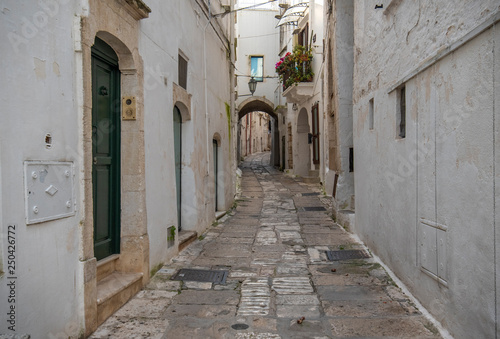 A street view of the old town - province of Brindisi, region of Apulia. Picturesque narrow with traditional white washed houses in the old historic center of Ostuni, Puglia, Italy
