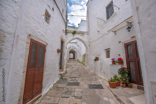 A street view of the old town - province of Brindisi, region of Apulia. Picturesque narrow with traditional white washed houses in the old historic center of Ostuni, Puglia, Italy © mitzo_bs