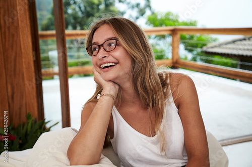 Young woman in glasses and white vest, smiling