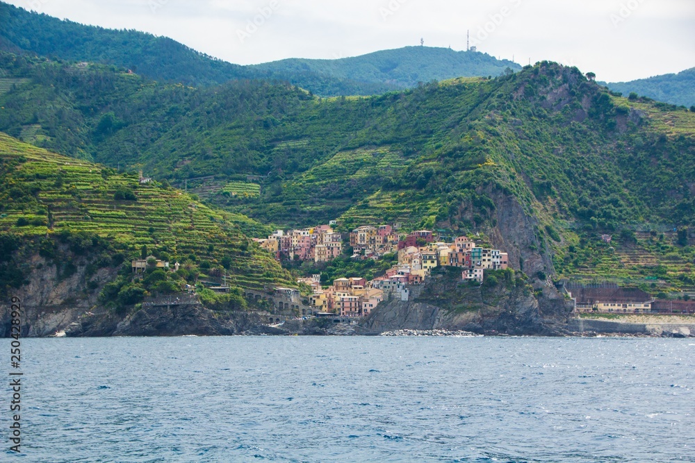 The town of Manarola, one of the five small towns in the Cinque Terre national Park, Italy. View from the excursion ship. Amazing colorful small town located in the mountains near the sea.
