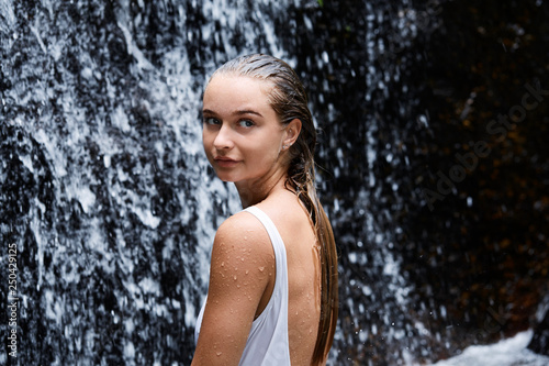 Gorgeous young woman looking away from waterfall