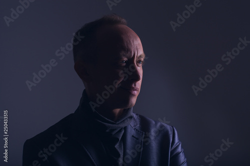 Model tests for men. Portrait of an adult male in a low key. Confident look with a smile and a smirk. Blue eyes. Color correction in purple-blue. Stylish image of an adult man