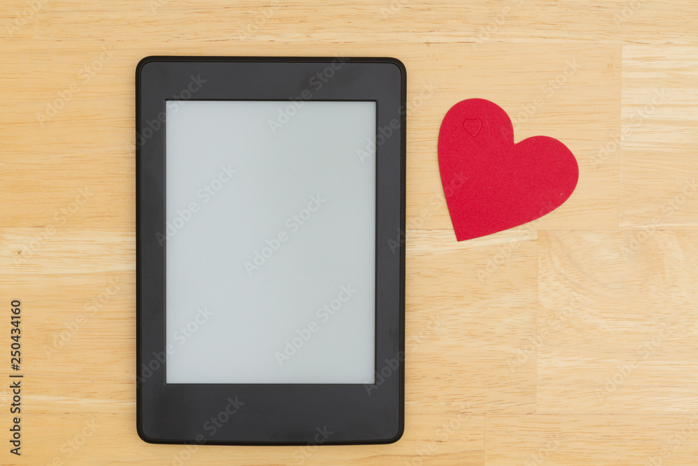 An e-reader on a wood desk with a heart An e-reader on a wood desk with a heart