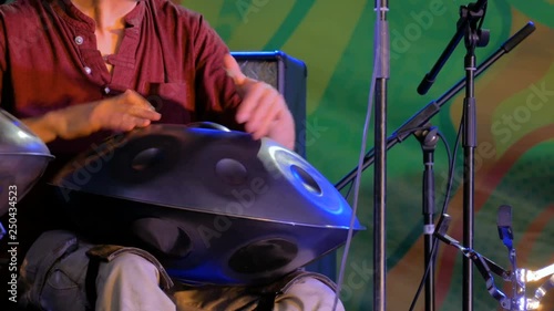 Man playing tank drum or hang on stage of ethnic open air concert. Relaxation, folk, meditative and traditional ethnic music concept photo