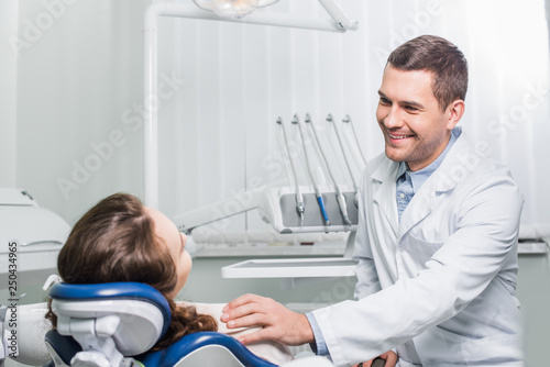 handsome dentist smiling while looking at patient