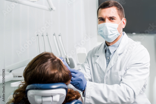 dentist in mask working with woman in latex gloves