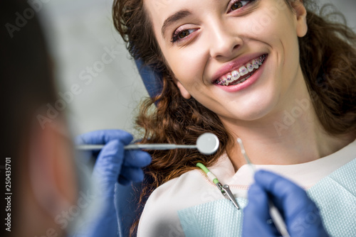 close up of cheerful woman in braces during examination of teeth near dentist photo