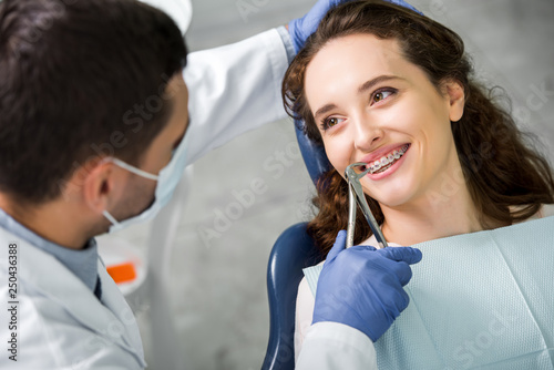 selective focus of woman smiling while looking at dentist during examination