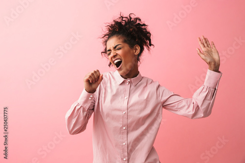Obraz na plátně Beautiful young african woman posing isolated over pink wall background screaming singing