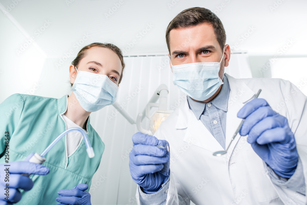 dentists in masks holding dental instruments in hands dentists in masks holding dental instruments in hands