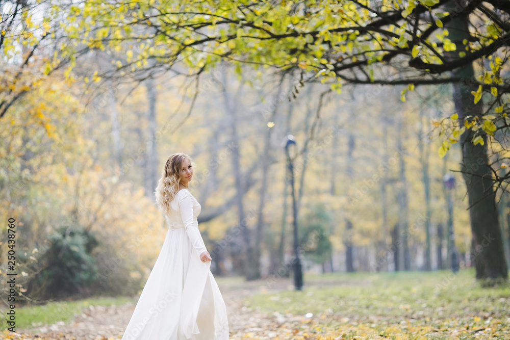 Look from behind at charming bride whirling in autumn park covered with fallen leaves Look from behind at charming bride whirling in autumn park covered with fallen leaves