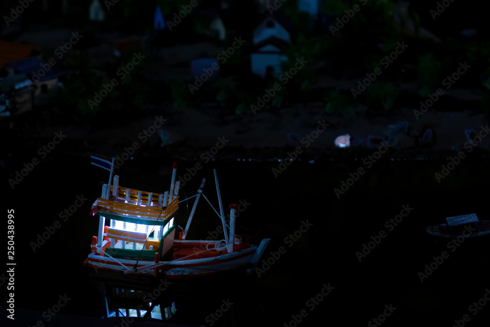 Fototapeta premium Model of fishing boats floating in the water at night