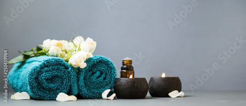 Spa still life with candles, towels and flowers on grey background copy space