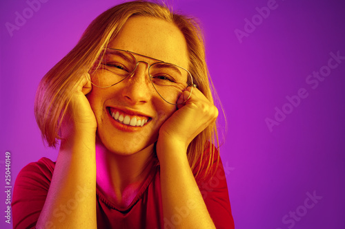 Happy business woman standing and smiling isolated on neon studio background. Beautiful female half-length portrait. Young emotional woman. The human emotions, facial expression concept