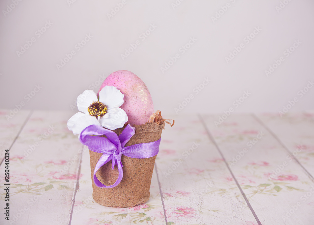 Naklejka premium Easter pink egg in a pot on the floral background