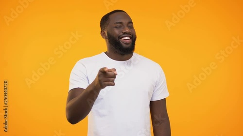 African american man pointing finger at camera and winking, smiling knowingly photo