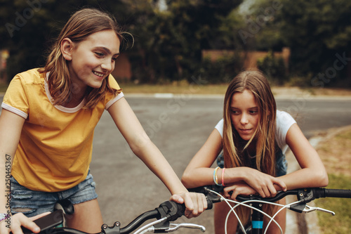 Two girls on bicycles on street photo