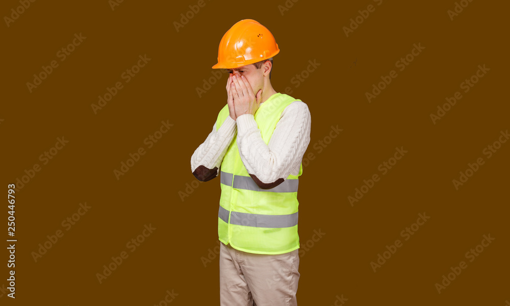 the man in a construction helmet and a vest sneezes