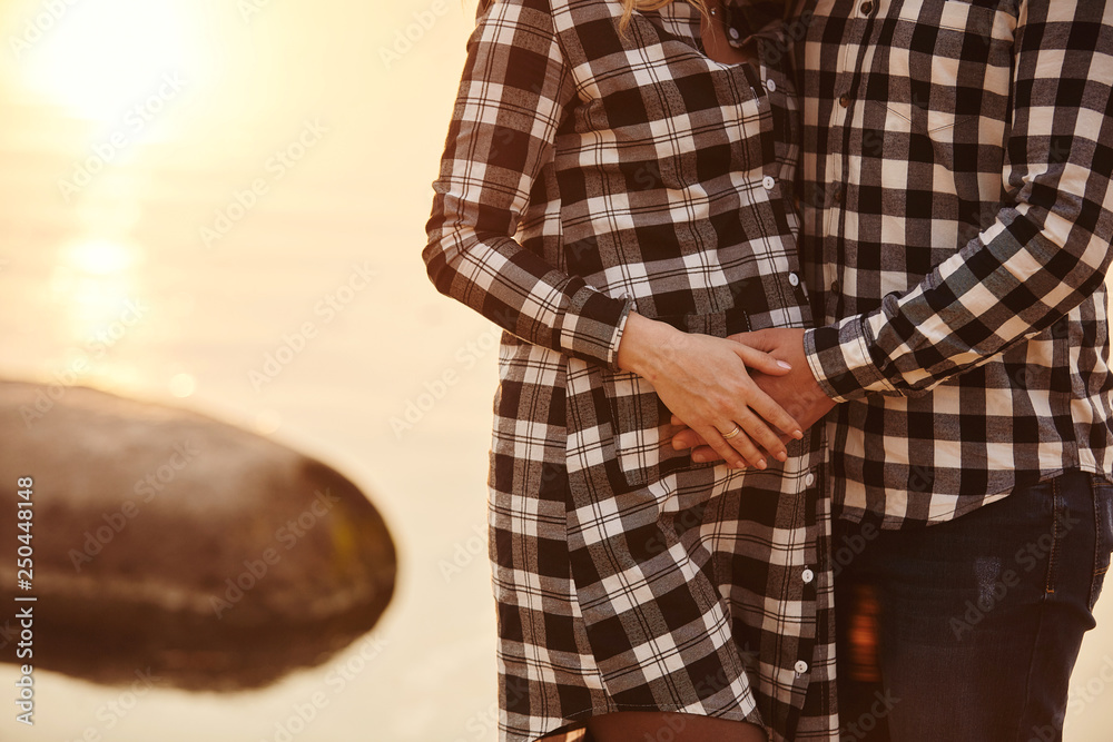 Young couple expecting baby hugging stomach. pregnancy and people concept
