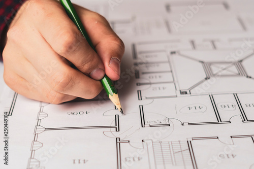 engineer sketching building project on a blueprint with a pencil b