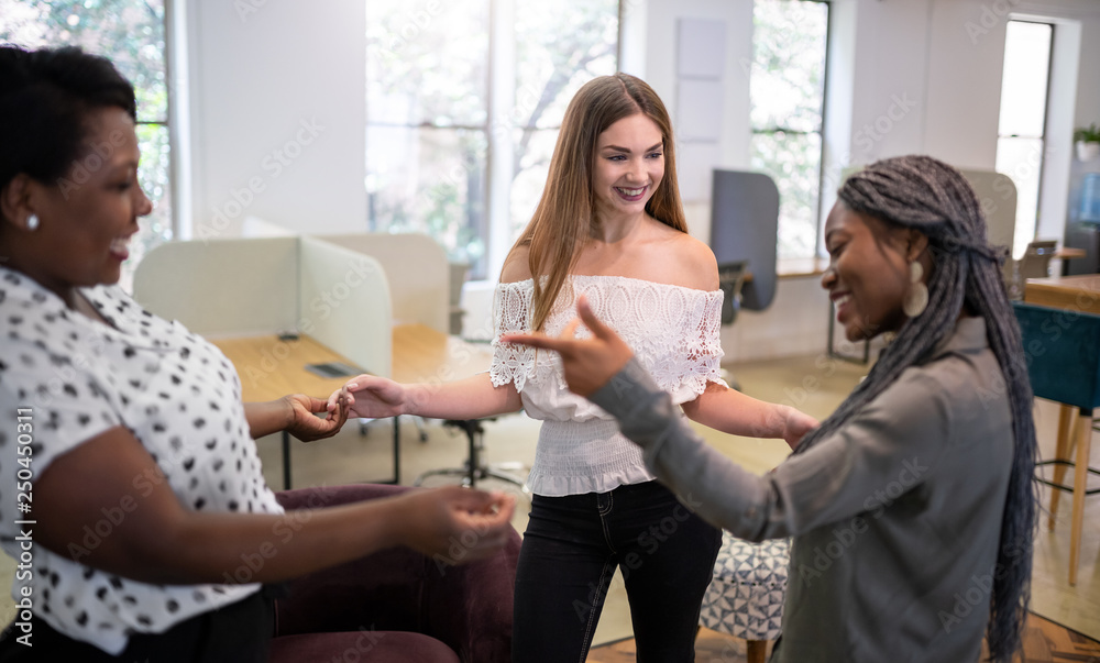 Woman friends greeting in a modern coworking space. Millennials dancing and smiling Woman friends greeting in a modern coworking space. Millennials dancing and smiling