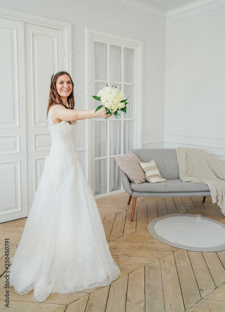 Beautiful smiling brunette woman bride in wedding dress with classical white roses bouquet, full length portrait Beautiful smiling brunette woman bride in wedding dress with classical white roses bouquet, full length portrait