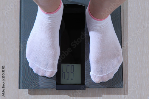 Human stands on an electronic scale.