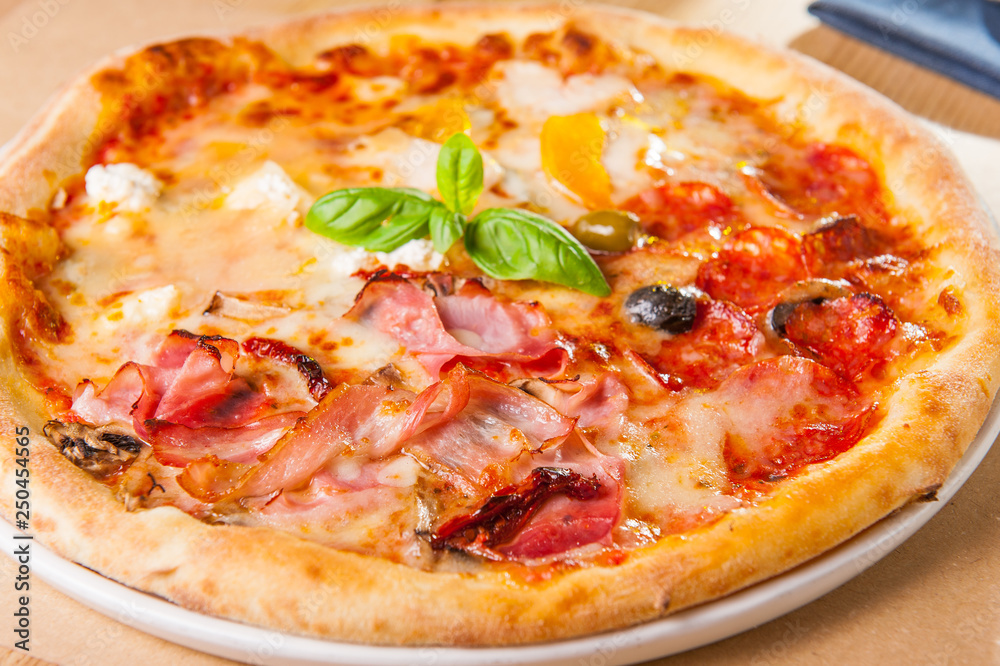 Selective focus close up Delicious Meat Pizza with bacon and sausages on white plate on the wooden table with cutlery and ingredients. Selective focus close up Delicious Meat Pizza with bacon and sausages on white plate on the wooden table with cutlery and ingredients.