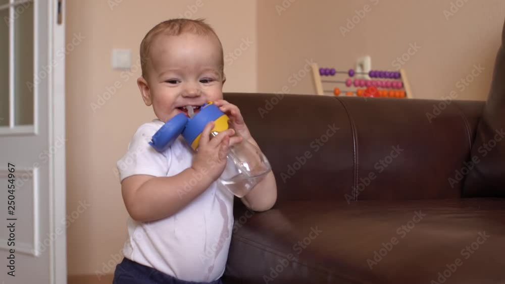 The little boy himself drinks water from a bottle and smiles sweetly The little boy himself drinks water from a bottle and smiles sweetly