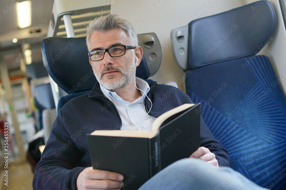 Mature man traveling by train, reading book Mature man traveling by train, reading book